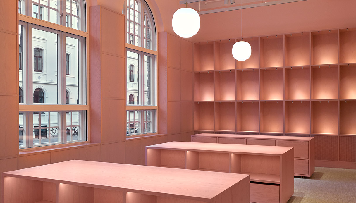 Intérieur de la librairie du musée Pomo avec des murs roses et des étagères illuminées