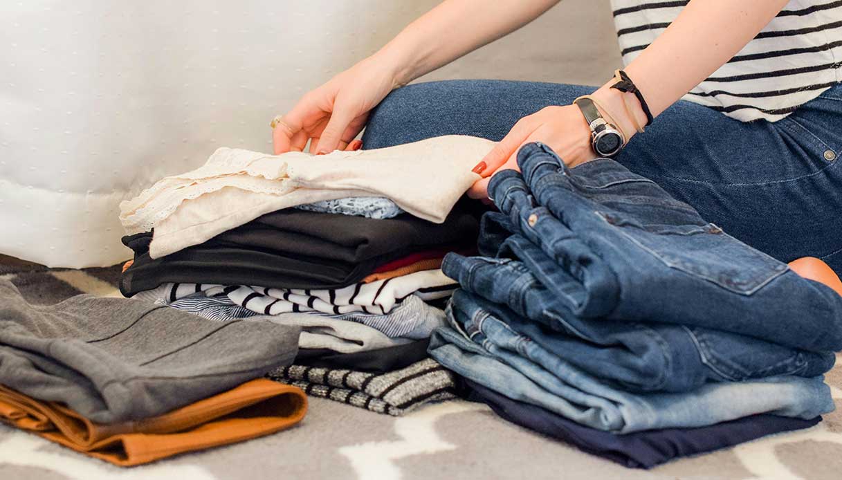 Femme pliant et organisant des vêtements sur un tapis, un geste symbolique de désencombrement
