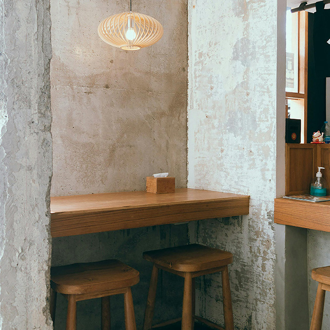 Petit coin déjeuner avec table en bois fixée sur le mur et les tabourets, idéal pour optimiser l'espace