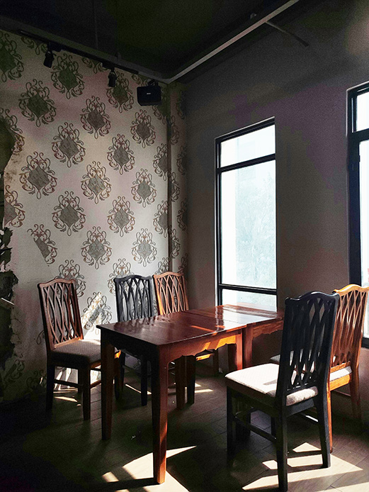 Salle à manger en bois avec mur décoré et lumière naturelle des fenêtres
