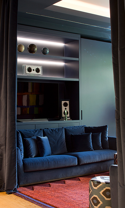 Salon avec canapé en velours bleu et bibliothèque intégrée dans un appartement de design à Brera