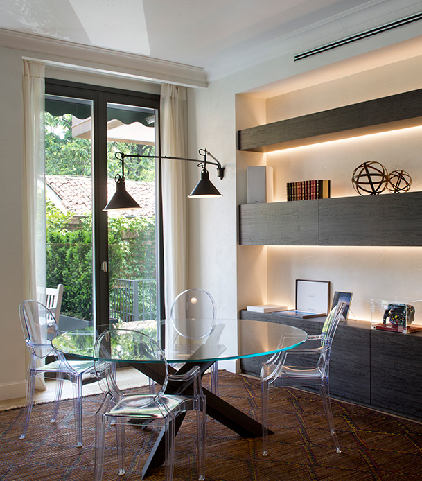 Salle à manger avec table de tulipe Eero Saarinen et chaises transparentes dans un appartement de luxe à Brera