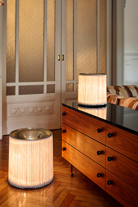 Lampes cylindriques aux franges lumineuses dans un intérieur élégant avec parquet et mobilier vintage