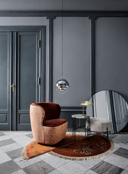 Salon élégant avec fauteuil bordeaux et rose, tapis circulaire et lampes métalliques suspendues